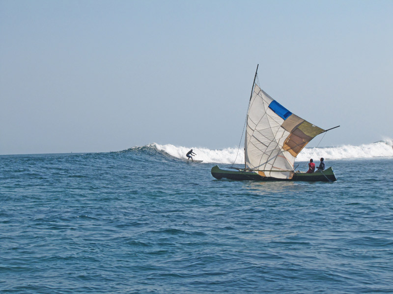 Surfeur en herbe sur la vague et devant le bateau